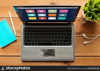 education, business, media and technology concept - close up of laptop computer with menu icons on screen on wooden table