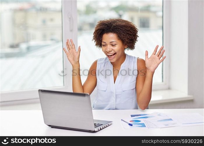 education, business, success and technology concept - happy african american businesswoman or student with laptop computer and papers at office