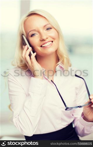 education, business, technology, communication and people concept - smiling businesswoman or secretary wearing eyeglasses calling on smartphone in office