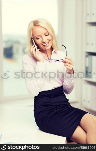 education, business, technology, communication and people concept - smiling businesswoman or secretary wearing eyeglasses calling on smartphone in office