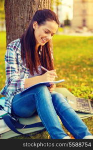education, campus and people concept - smiling teenager writing in notebook
