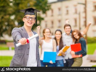 education, campus and teenage concept - smiling teenage boy in corner-cap and eyeglasses with diploma and classmates on the back
