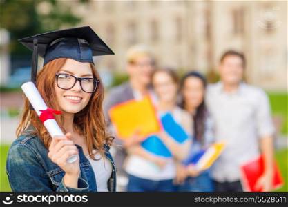 education, campus and teenage concept - smiling teenage girl in corner-cap and eyeglasses with diploma and classmates on the back