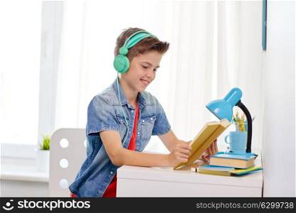 education, childhood and people concept - happy student boy in headphones reading book at home. student boy in headphones reading book at home