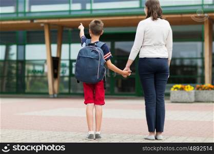 education, childhood, family and people concept - elementary student boy with mother at school yard