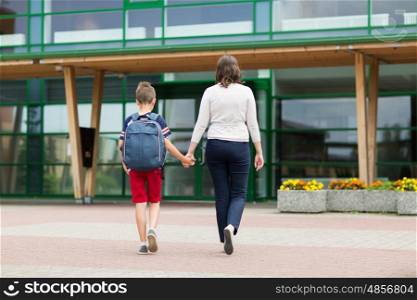education, childhood, family and people concept - elementary student boy with mother going to school