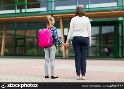 education, childhood, family and people concept - elementary student girl with mother at school yard