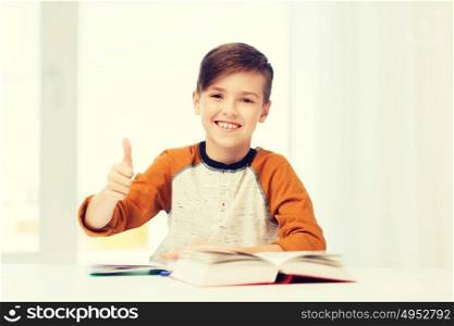 education, childhood, people and school concept - happy student boy with textbook and notebook showing thumbs up at home. happy student boy with textbook showing thumbs up
