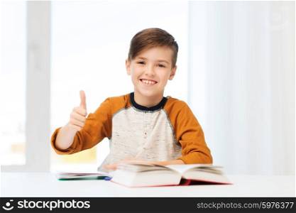 education, childhood, people and school concept - happy student boy with textbook and notebook showing thumbs up at home