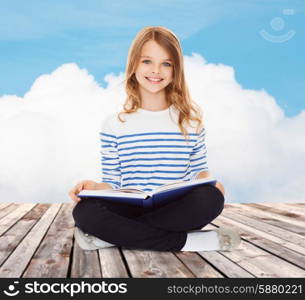 education, childhood, people and school concept - little student girl studying and reading book over blue sky and cloud background