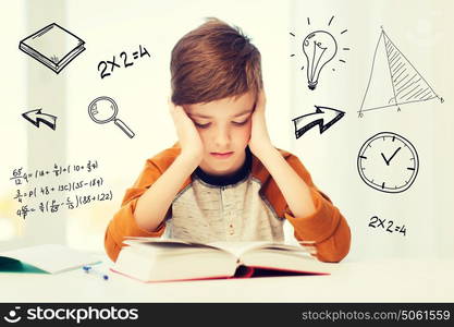 education, childhood, people, homework and school concept - bored student boy reading book or textbook at home over mathematical doodles. student boy reading book or textbook at home