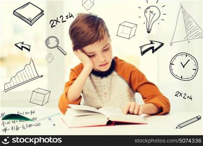 education, childhood, people, homework and school concept - bored student boy reading book or textbook at home over mathematical doodles. student boy reading book or textbook at home