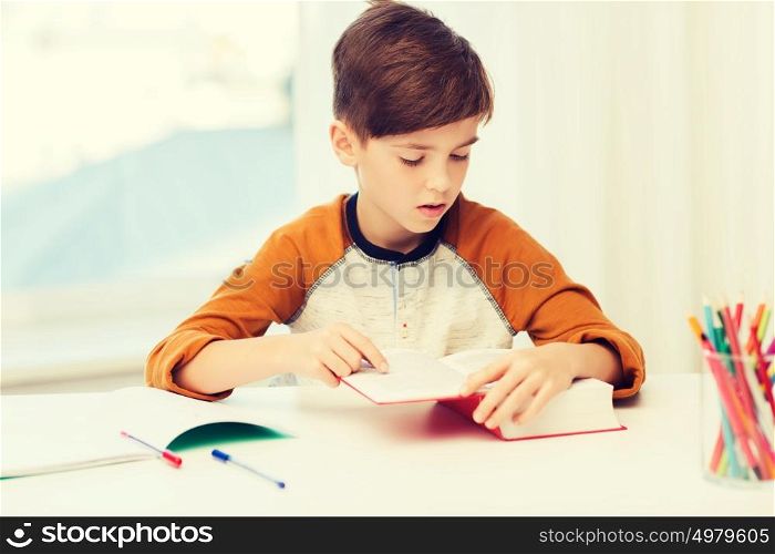 education, childhood, people, homework and school concept - student boy reading book or textbook at home. student boy reading book or textbook at home