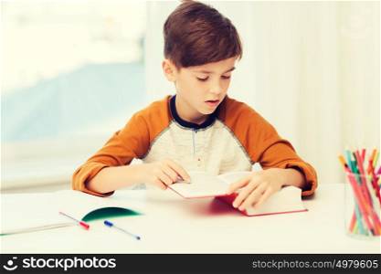 education, childhood, people, homework and school concept - student boy reading book or textbook at home. student boy reading book or textbook at home