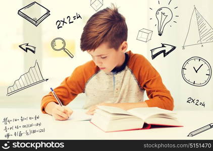 education, childhood, people, homework and school concept - student boy with book writing to notebook at home over mathematical doodles. student boy with book writing to notebook at home