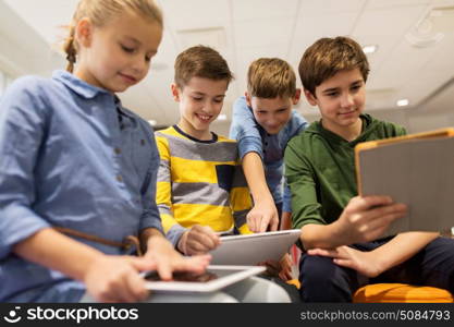 education, children, technology and people concept - group of happy kids with tablet pc computers learning at school. group of happy children with tablet pc at school. group of happy children with tablet pc at school