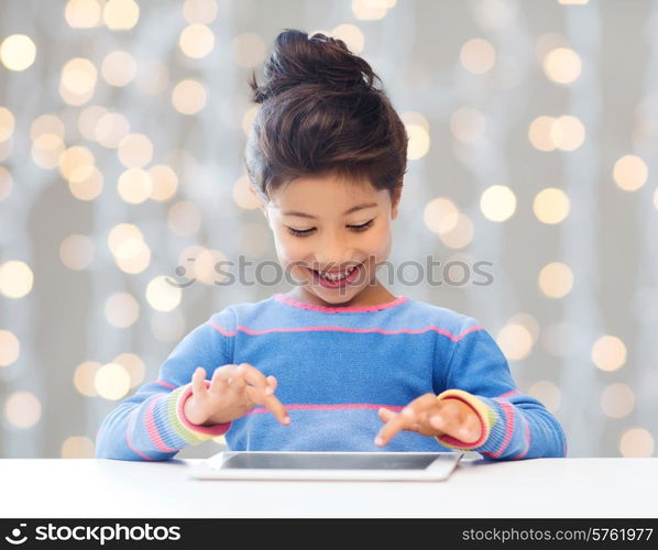 education, children, technology and people concept - happy little girl with tablet pc computer over holidays lights background