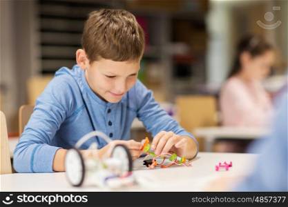 education, children, technology, science and people concept - close up of boy building robot at robotics school lesson