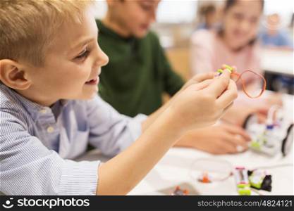 education, children, technology, science and people concept - close up of happy boy building robot at robotics school lesson