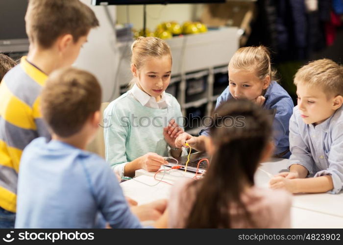 education, children, technology, science and people concept - group of happy kids building robots at robotics school lesson