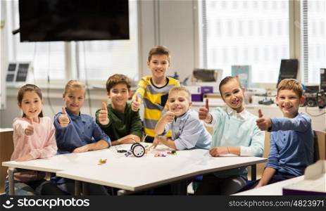 education, children, technology, science and people concept - group of happy kids building robots at robotics school lesson and showing thumbs up
