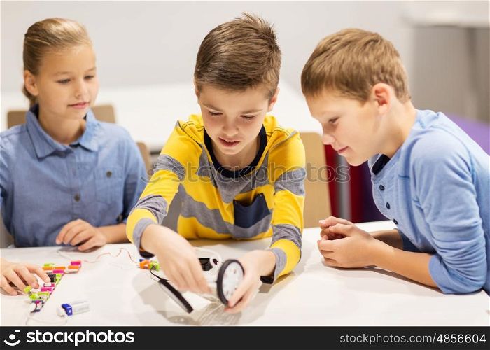 education, children, technology, science and people concept - group of happy kids building robots at robotics school lesson