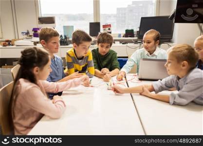 education, children, technology, science and people concept - group of happy kids with laptop computer playing and invention kit at robotics school lesson