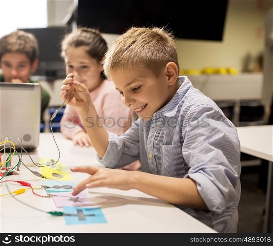 education, children, technology, science and people concept - group of happy kids with laptop computer playing with invention kit at robotics school lesson