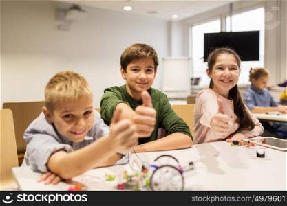 education, children, technology, science and people concept - group of happy kids building robots at robotics school lesson and showing thumbs up. happy children building robots at robotics school