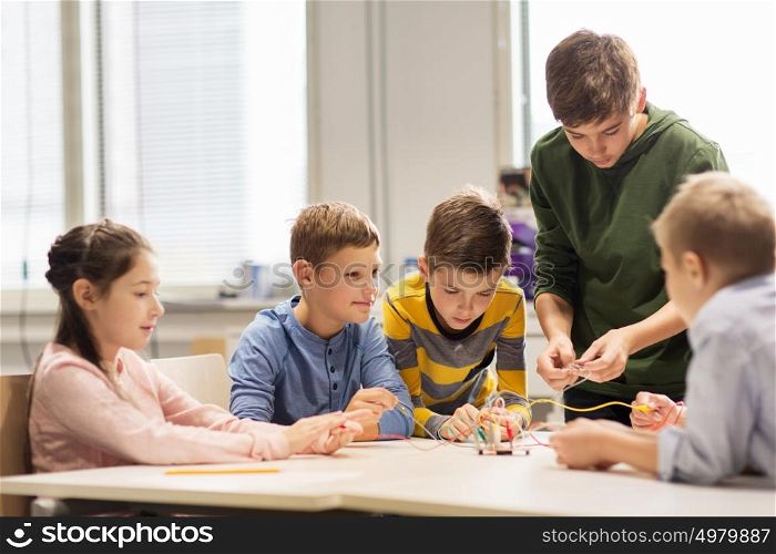 education, children, technology, science and people concept - group of happy kids building robots at robotics school lesson. happy children building robots at robotics school