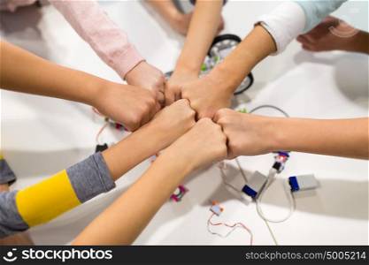 education, children, technology, science and people concept - group of happy kids with building kit making fist bump at robotics school. happy children making fist bump at robotics school