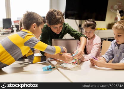 education, children, technology, science and people concept - group of happy kids with laptop computer playing and invention kit at robotics school lesson. kids with invention kit at robotics school