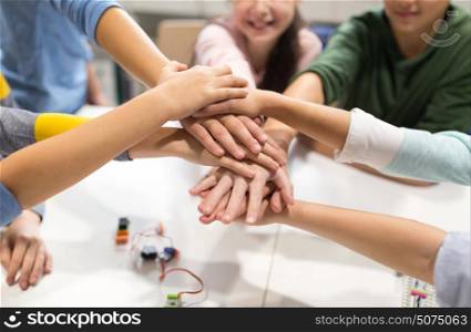education, children, technology, science and people concept - group of happy kids building robots l at robotics lesson and holding hands together. happy children holding hands at robotics school