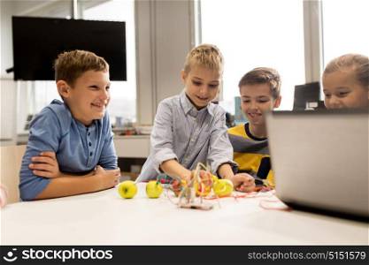 education, children, technology, science and people concept - group of happy kids with laptop computer playing and invention kit at robotics school lesson. kids with invention kit at robotics school