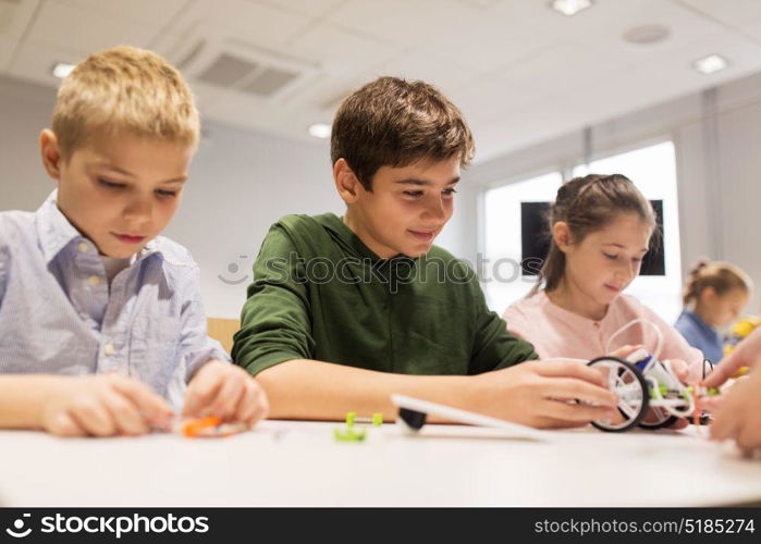 education, children, technology, science and people concept - group of happy kids building robots at robotics school lesson. happy children building robots at robotics school