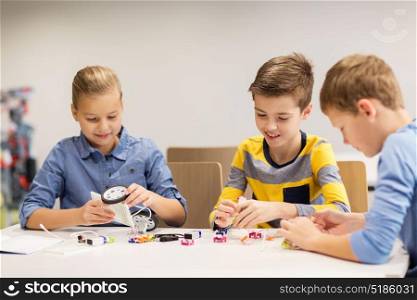 education, children, technology, science and people concept - group of happy kids building robots at robotics school lesson. happy children building robots at robotics school