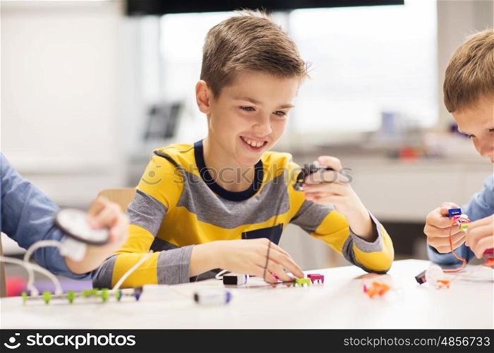 education, children, technology, science and people concept - happy boy building robot at robotics school lesson
