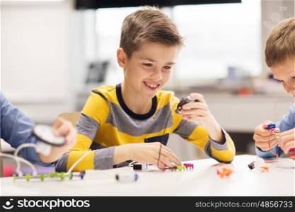 education, children, technology, science and people concept - happy boy building robot at robotics school lesson