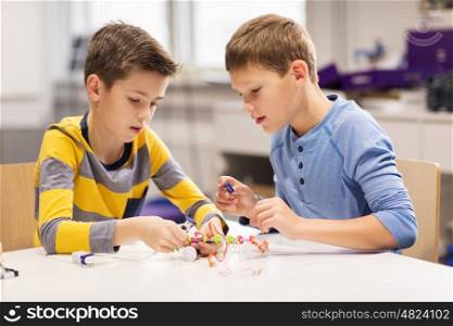 education, children, technology, science and people concept - happy boys building robots at robotics school lesson