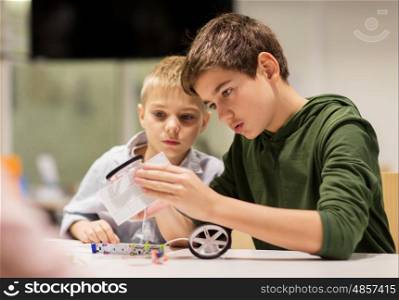 education, children, technology, science and people concept - happy boys building robots at robotics school lesson
