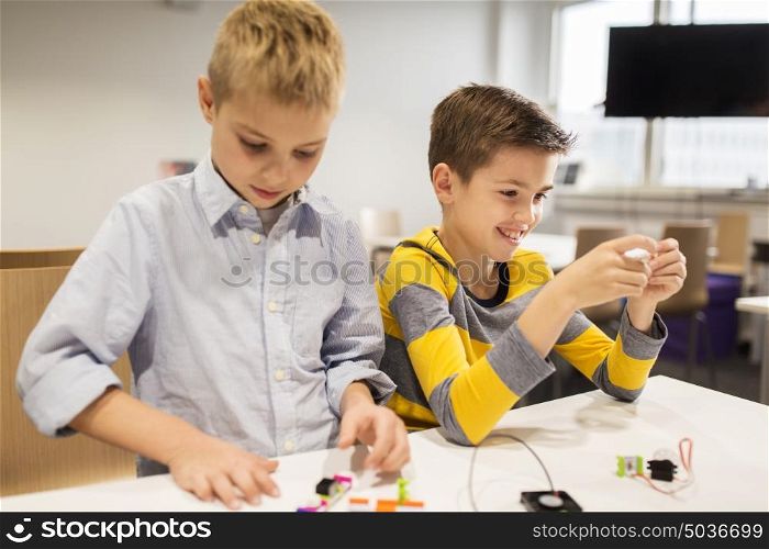 education, children, technology, science and people concept - happy boys building robots at robotics school lesson. happy children building robots at robotics school