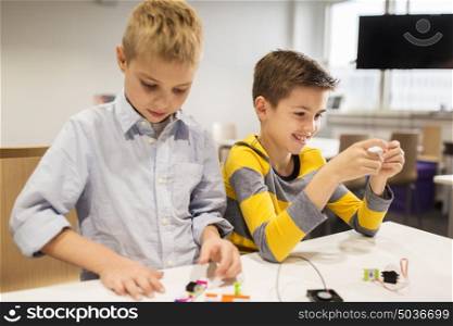 education, children, technology, science and people concept - happy boys building robots at robotics school lesson. happy children building robots at robotics school