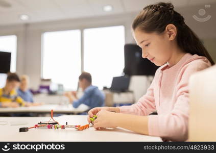 education, children, technology, science and people concept - happy girl building robot at robotics school lesson