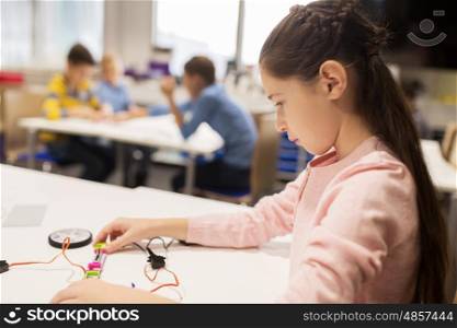 education, children, technology, science and people concept - happy girl building robot at robotics school lesson
