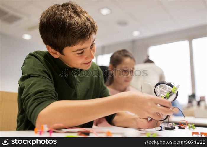 education, children, technology, science and people concept - happy kids building robot at robotics school lesson. happy children building robot at robotics school