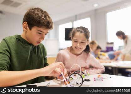 education, children, technology, science and people concept - happy kids building robots at robotics school lesson