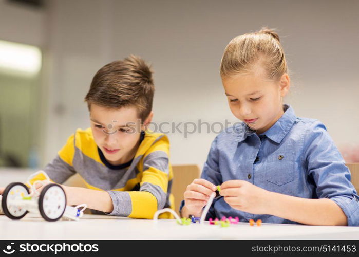 education, children, technology, science and people concept - happy kids building robots at robotics school lesson. happy children building robots at robotics school