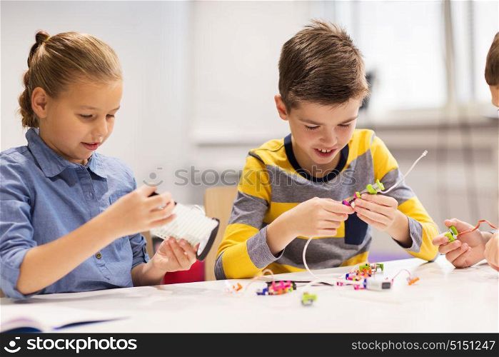 education, children, technology, science and people concept - happy kids building robots at robotics school lesson. happy children building robots at robotics school