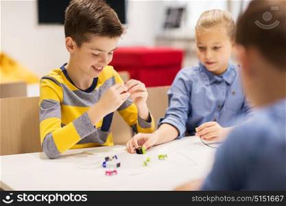 education, children, technology, science and people concept - happy kids building robots at robotics school lesson. happy children building robots at robotics school