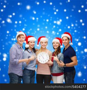 education, christmas, happiness and people concept - group of smiling students in santa helper hats with clock showing 12